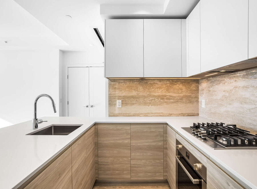 Experience modern luxury in this stunning kitchen, featuring sleek white countertops and a striking travertine backsplash.