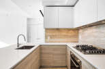 Experience modern luxury in this stunning kitchen, featuring sleek white countertops and a striking travertine backsplash.