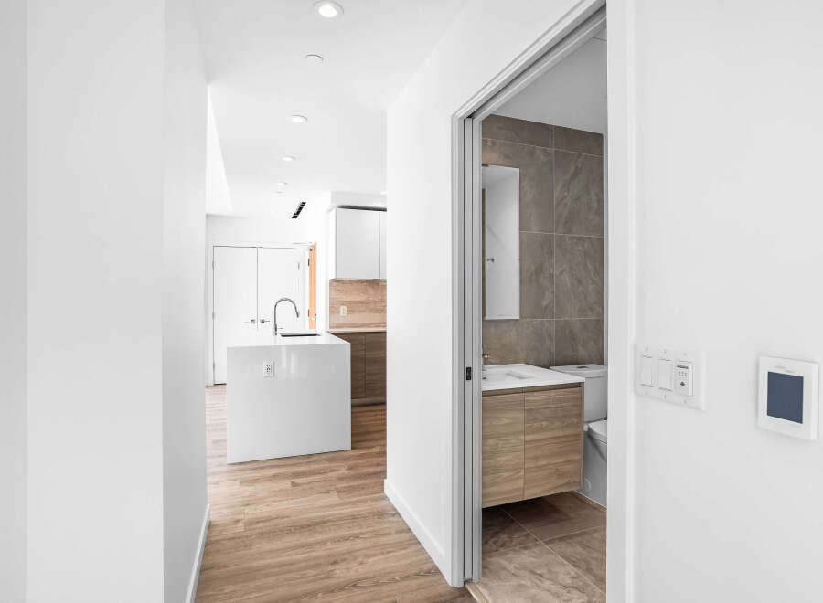 Step into a modern oasis featuring a sleek white kitchen island with a contemporary faucet, complemented by warm wood cabinetry and elegant marble-look flooring.