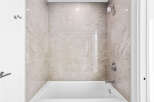 Experience modern comfort in this beautifully tiled bathroom, featuring a sleek bathtub and a rainfall showerhead for a spa-like experience.