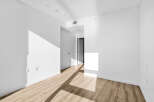 Step into this bright and airy living space, featuring pristine white walls and a modern light wood floor.