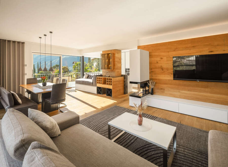 Experience modern living in this spacious open-plan apartment, featuring a dining area with stunning mountain views and a cozy living room with a contemporary fireplace.