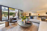Experience luxurious indoor-outdoor living in this stunning modern residence, featuring expansive glass doors that seamlessly connect the elegant living space to a beautifully landscaped patio.