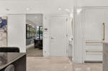 Step into a modern entryway featuring a sleek white door with brushed gold hardware, complemented by a mirrored sliding door that opens to a sophisticated dining area.