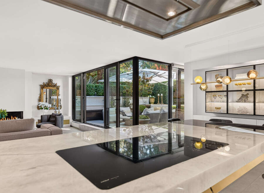 Experience luxurious living in this stunning home, featuring a modern kitchen island with a sleek induction cooktop and a sophisticated dining area.