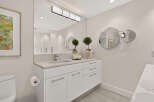 This modern bathroom features a sleek white vanity with a stone countertop and a minimalist faucet.