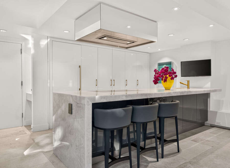 Experience luxury in this modern kitchen featuring sleek white cabinetry and a stunning marble island.