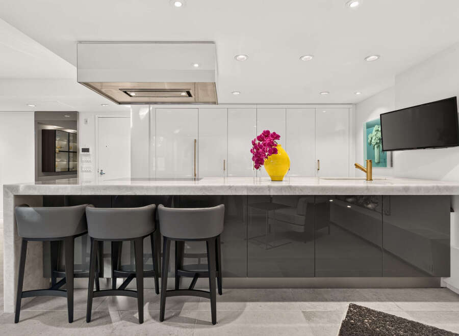 Experience modern luxury in this stunning kitchen, featuring sleek, high-gloss cabinetry and a striking marble waterfall island.
