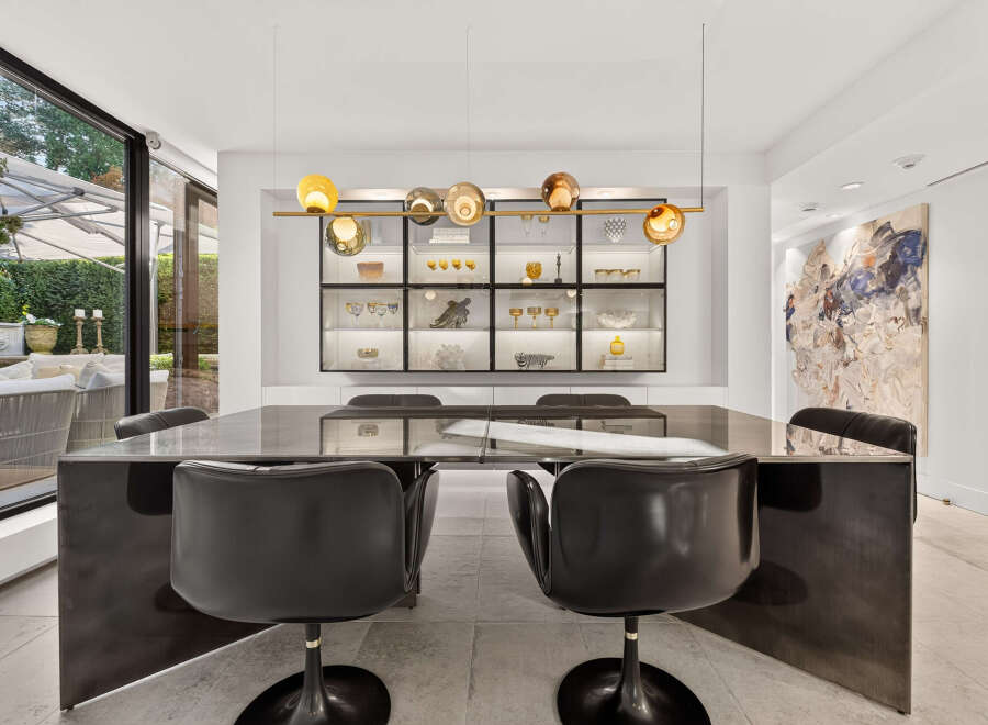 Experience sophisticated dining in this modern space, featuring a sleek, dark dining table with plush black chairs.