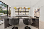 Experience sophisticated dining in this modern space, featuring a sleek, dark dining table with plush black chairs.