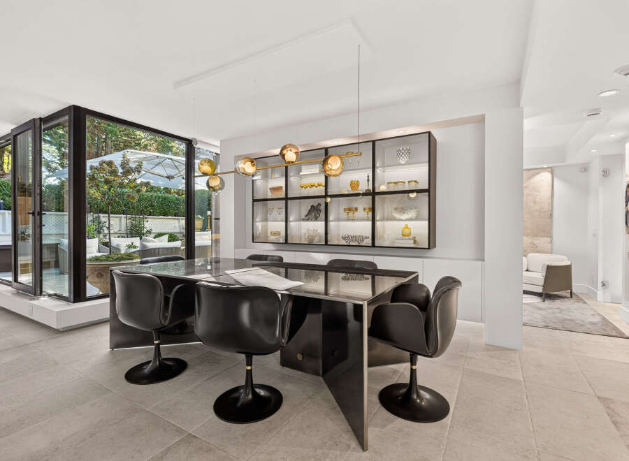 Experience modern elegance in this dining area, featuring a sleek black dining table with matching chairs and a stunning glass-fronted display cabinet illuminated with soft lighting.