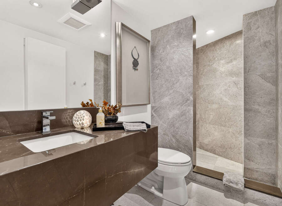 Experience luxury in this modern bathroom, featuring a sleek brown marble vanity with an integrated sink and a contemporary chrome faucet.