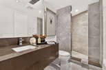 Experience luxury in this modern bathroom, featuring a sleek brown marble vanity with an integrated sink and a contemporary chrome faucet.
