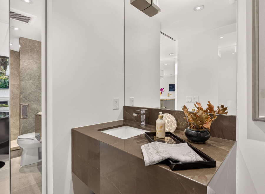 Experience modern luxury in this stunning bathroom, featuring a sleek vanity with a stone countertop and a vessel sink.