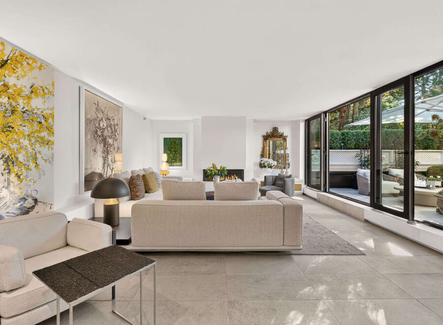 Experience luxurious living in this spacious living room, featuring a modern fireplace and large windows that open to a beautifully landscaped patio.