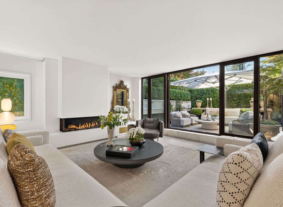 Experience luxurious living in this stunning modern living room, featuring a sleek linear fireplace and expansive sliding glass doors that open to a beautifully landscaped patio.