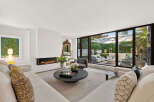 Experience luxurious living in this stunning modern living room, featuring a sleek linear fireplace and expansive sliding glass doors that open to a beautifully landscaped patio.