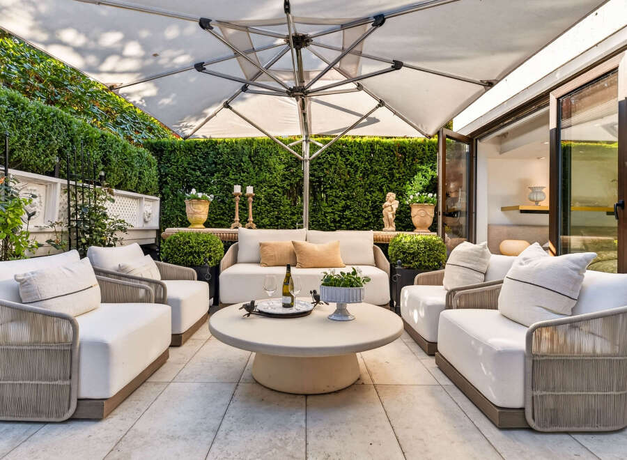Experience luxurious outdoor living with this beautifully appointed patio space, featuring plush white seating arranged around a chic round coffee table.
