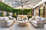 Experience luxurious outdoor living with this beautifully appointed patio space, featuring plush white seating arranged around a chic round coffee table.