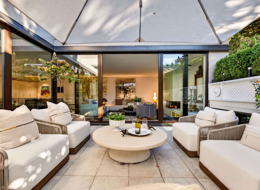 Experience seamless indoor-outdoor living with this stunning patio space, featuring comfortable seating and a large umbrella for shade.