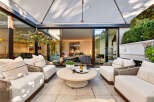 Experience seamless indoor-outdoor living with this stunning patio space, featuring comfortable seating and a large umbrella for shade.