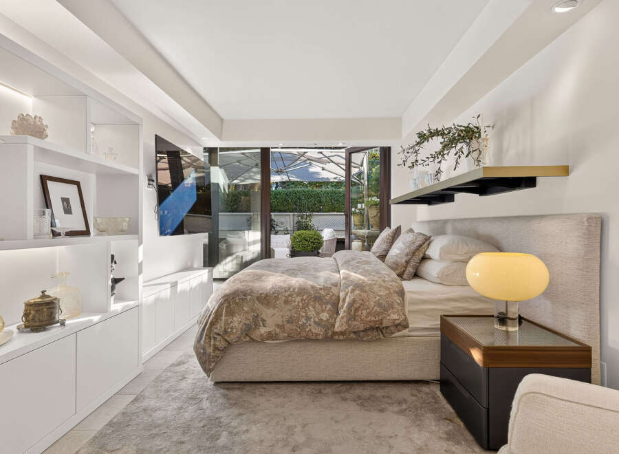 Experience luxury in this master bedroom, featuring a plush king-sized bed with a textured headboard and a beautiful floral duvet.