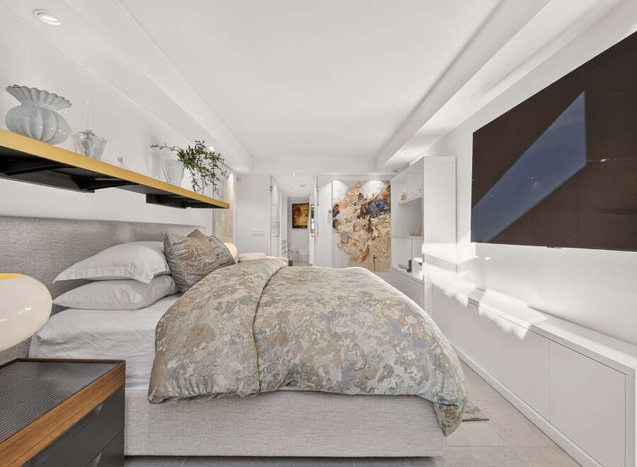 Experience luxury in this master bedroom, featuring a king-size bed with crisp white linens and a plush duvet.