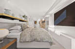 Experience luxury in this master bedroom, featuring a king-size bed with crisp white linens and a plush duvet.