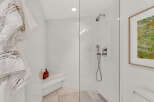 Experience luxury in this modern bathroom featuring a spacious glass-enclosed shower with a built-in bench and a sleek rainfall showerhead.