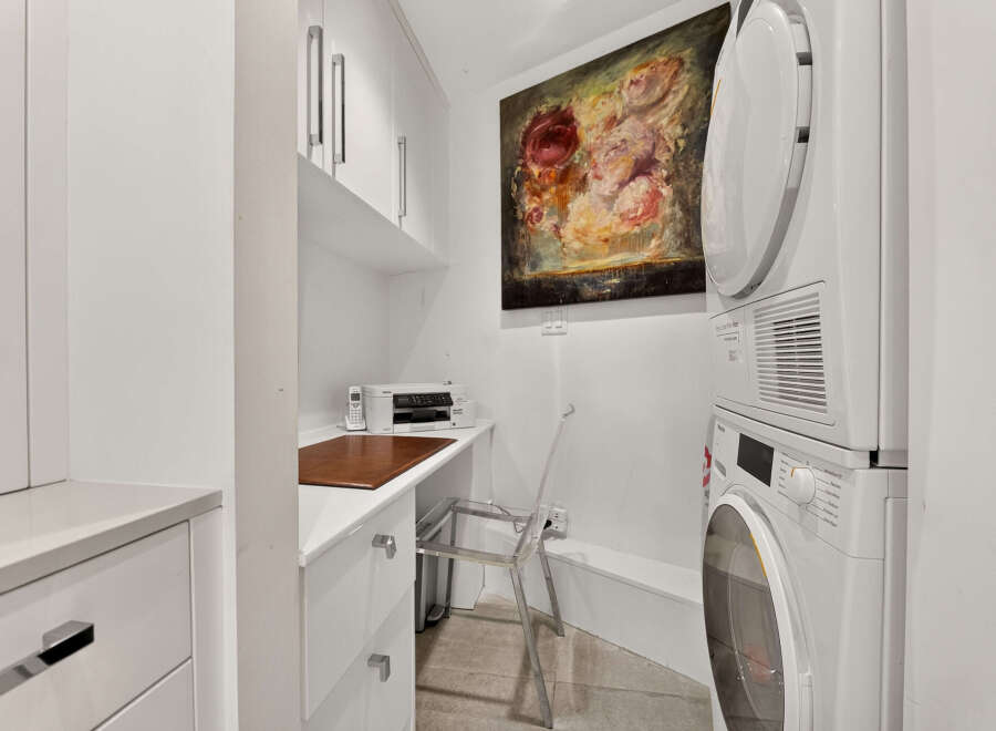 This laundry room offers a practical and stylish setup with a stacked washer and dryer, perfect for maximizing space.
