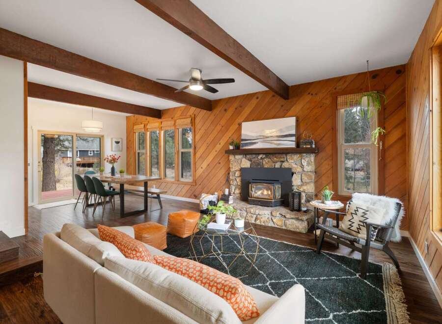 Experience rustic charm in this inviting living space, featuring a striking stone fireplace with a wood-burning insert and exposed wooden beams that add warmth and character.