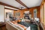 Experience rustic charm in this inviting living space, featuring a striking stone fireplace with a wood-burning insert and exposed wooden beams that add warmth and character.