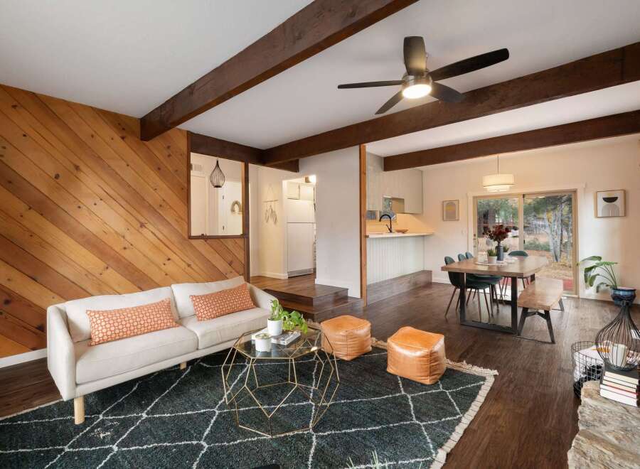 Experience the warmth of this inviting living space, featuring a striking diagonal wood-paneled accent wall and exposed wooden beams that add rustic charm.