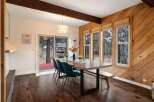 This dining room features a rustic charm with its warm wood-paneled walls and exposed wooden beams.