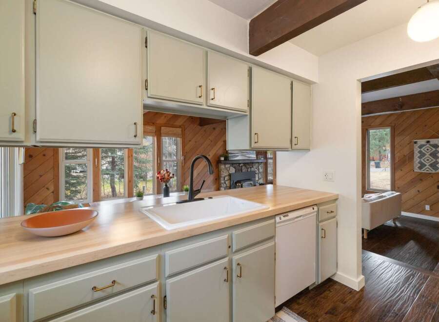This charming kitchen boasts a spacious farmhouse sink and a butcher block countertop, perfect for meal preparation.