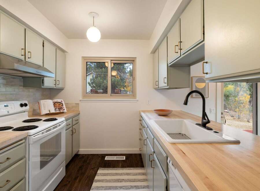 This charming kitchen boasts light sage green cabinetry complemented by warm butcher block countertops.