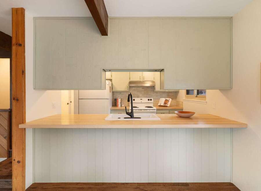 Discover this charming kitchen featuring a spacious butcher block countertop perfect for meal prep and casual dining.