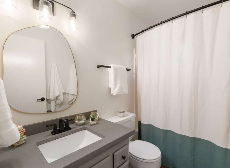 This modern bathroom features a sleek gray vanity with a white undermount sink and a matte black faucet.