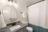 This modern bathroom features a sleek gray vanity with a white undermount sink and a matte black faucet.