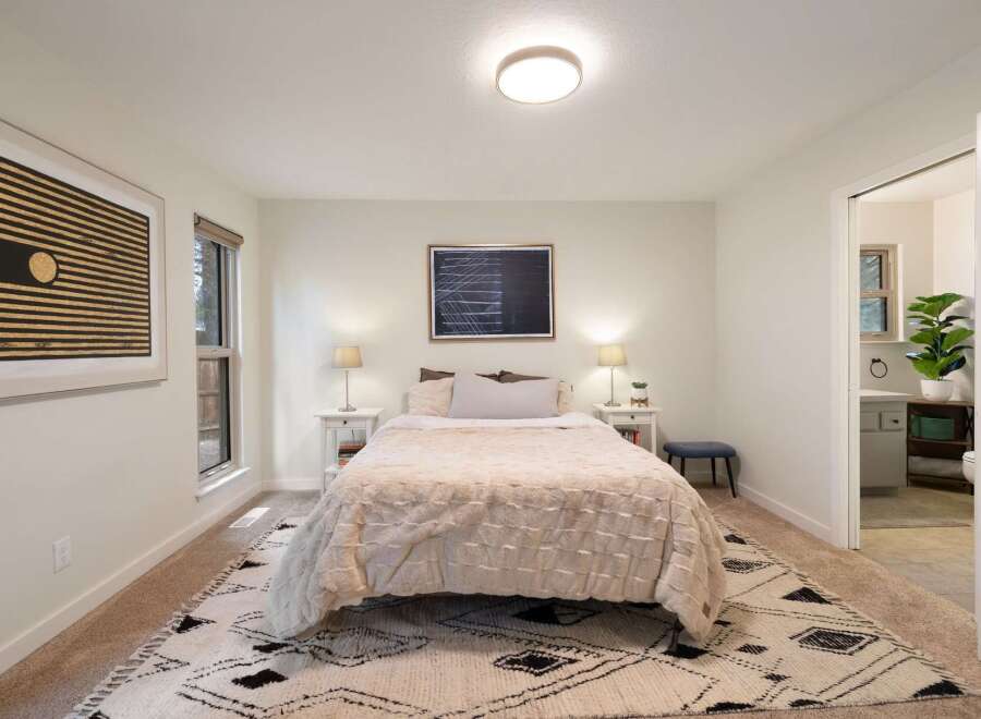 This inviting bedroom features a plush queen-size bed adorned with a cozy, textured duvet and a stylish geometric rug.