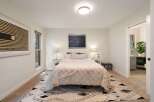 This inviting bedroom features a plush queen-size bed adorned with a cozy, textured duvet and a stylish geometric rug.