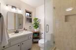 This charming bathroom features a modern vanity with ample storage and a sleek black faucet, complemented by a large, rounded mirror.