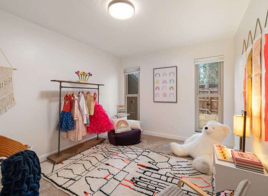 This charming children's bedroom features a playful clothing rack filled with colorful outfits, perfect for a little one's dress-up adventures.