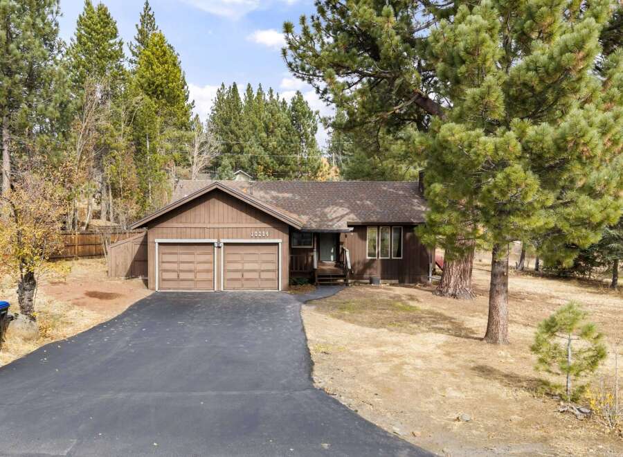 Nestled among mature pine trees, this charming brown home offers a serene retreat.