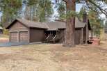 Nestled amongst tall pine trees, this charming brown home offers a serene retreat.