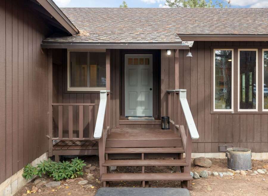 Welcome to this charming home featuring a welcoming front porch with a light blue door, perfect for greeting guests.