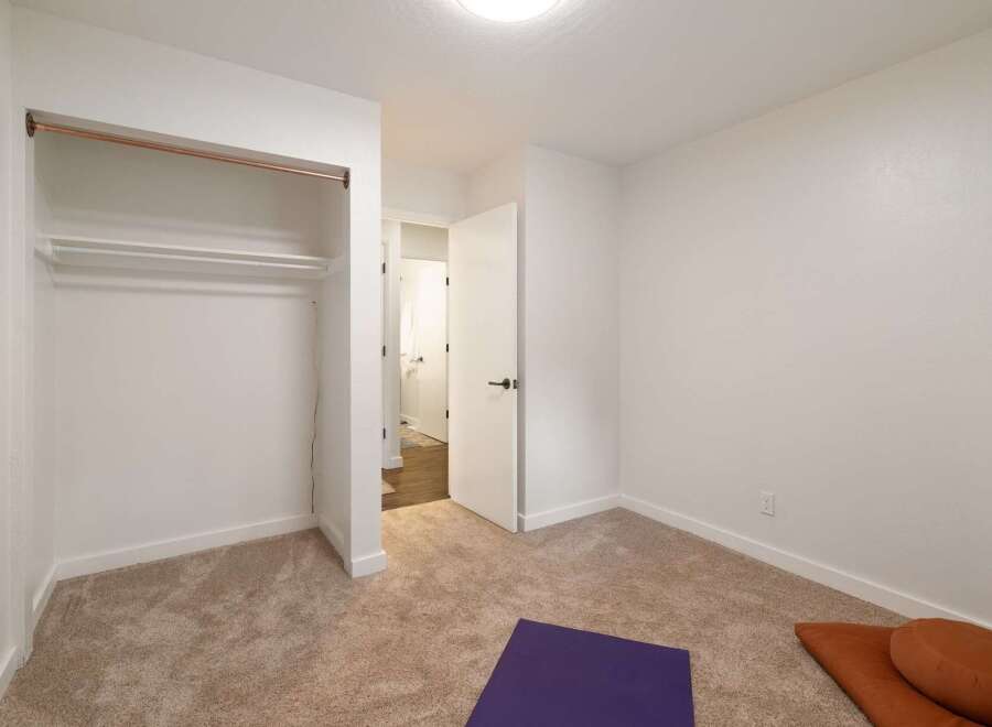 This unfurnished bedroom offers a blank canvas for your personal style, featuring a spacious closet with a copper rod and a secondary shelf.