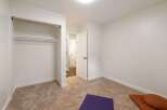 This unfurnished bedroom offers a blank canvas for your personal style, featuring a spacious closet with a copper rod and a secondary shelf.