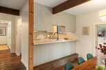 This charming kitchen features light green paneled cabinets and a butcher block countertop, creating a warm and inviting atmosphere.