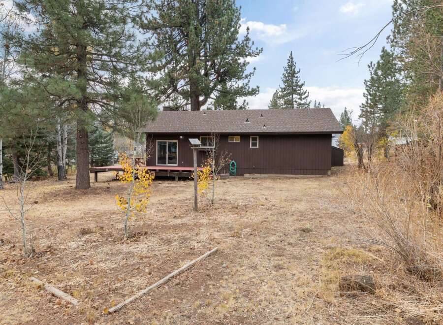 This charming brown home features a spacious wooden deck, perfect for outdoor entertaining and enjoying the surrounding natural beauty.